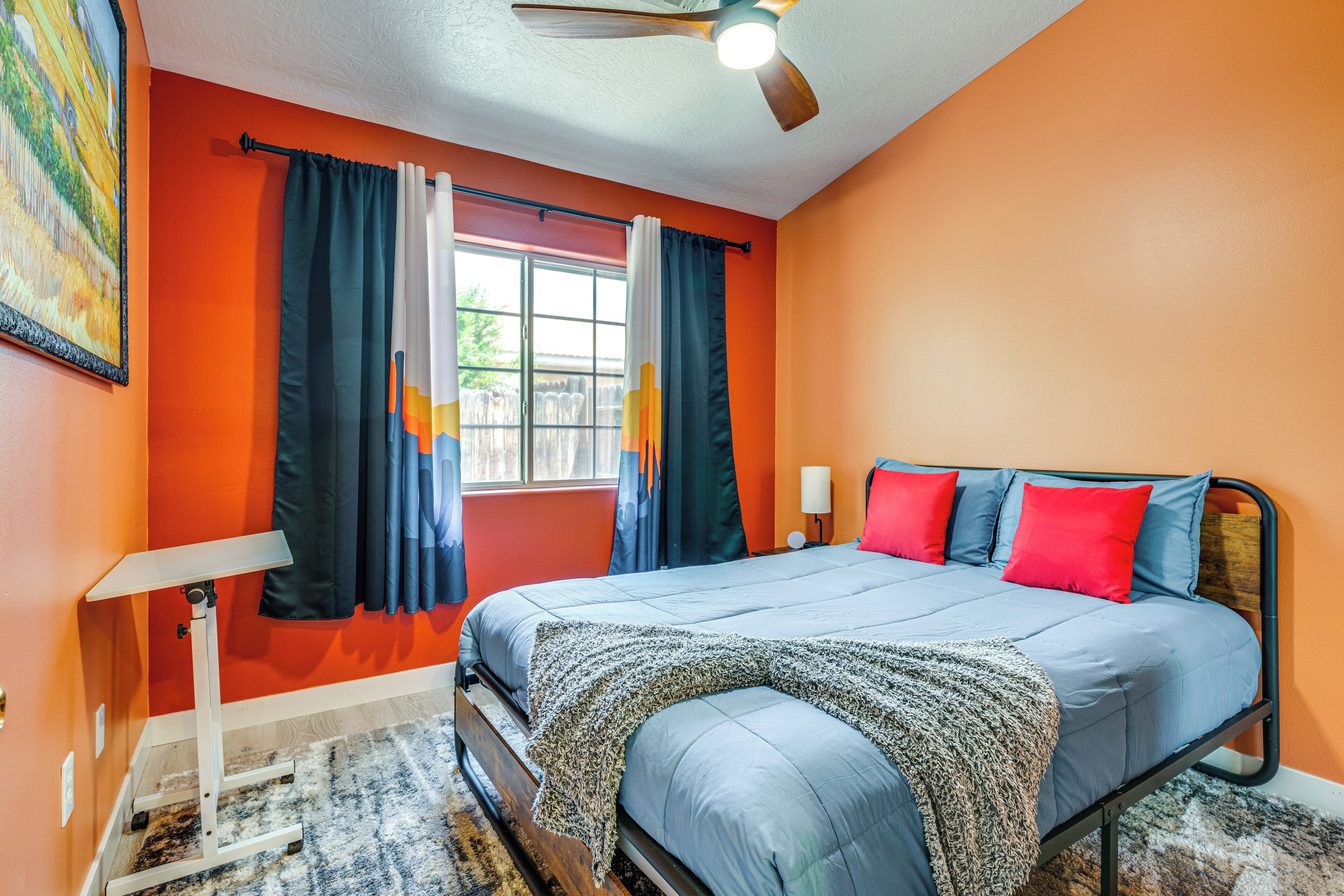 Un dormitorio con cama, cortinas, ventilador de techo y ventana.