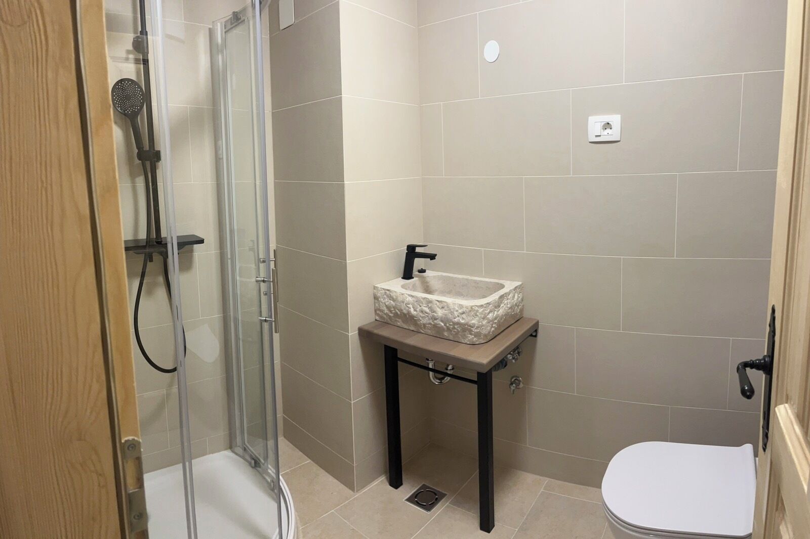 Une petite salle de bain avec une douche à parois de verre, un lavabo doté d’un plan de toilette imitant le marbre et des toilettes.