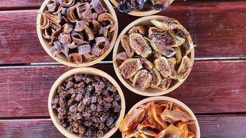 Seven wooden bowls containing various dried fruits and vegetables arranged on a wooden surface.