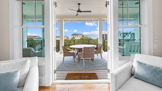 A covered patio with a table and chairs, a ceiling fan, and a view of a house and greenery. - One Second Away|Easy Beach Access|Gulf Views|Private Pool (Santa Rosa Beach)