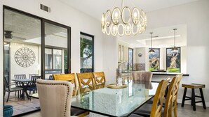 Un espace repas moderne avec une table à plateau en verre, des chaises en bois et un lustre.