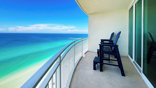 Un balcon avec vue sur l’océan, une balustrade et deux chaises.