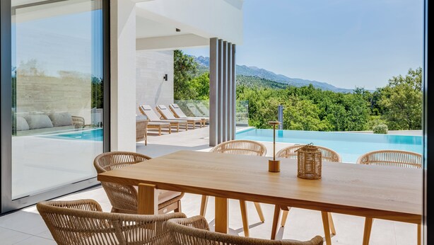 A modern outdoor dining area with a wooden table and wicker chairs, overlooking a swimming pool and lush greenery. - NEW Luxury villa I infinity pool (Starigrad)