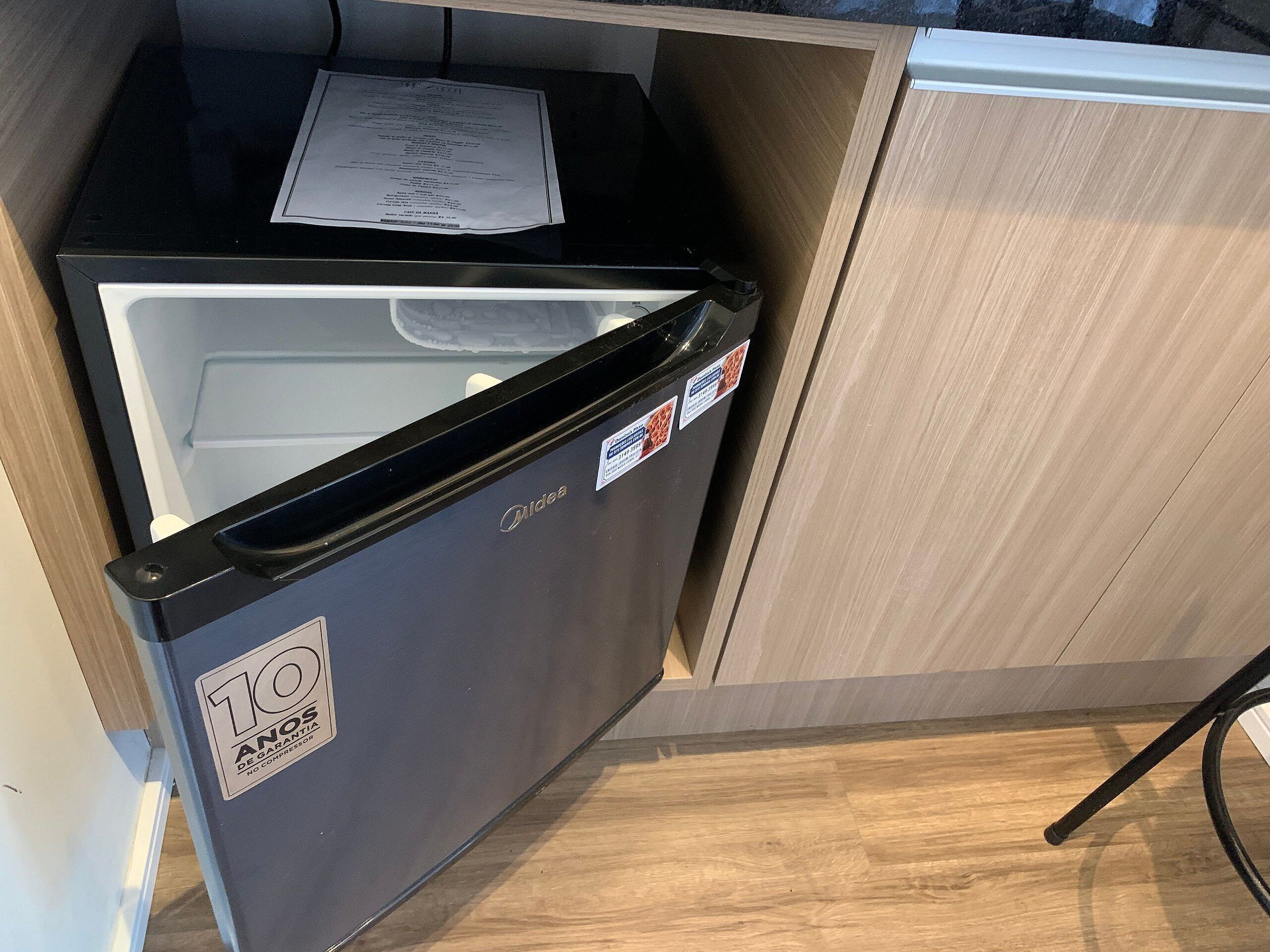 Un petit réfrigérateur, doté d’une étiquette indiquant une garantie de 10 ans, placé dans un meuble en bois.
