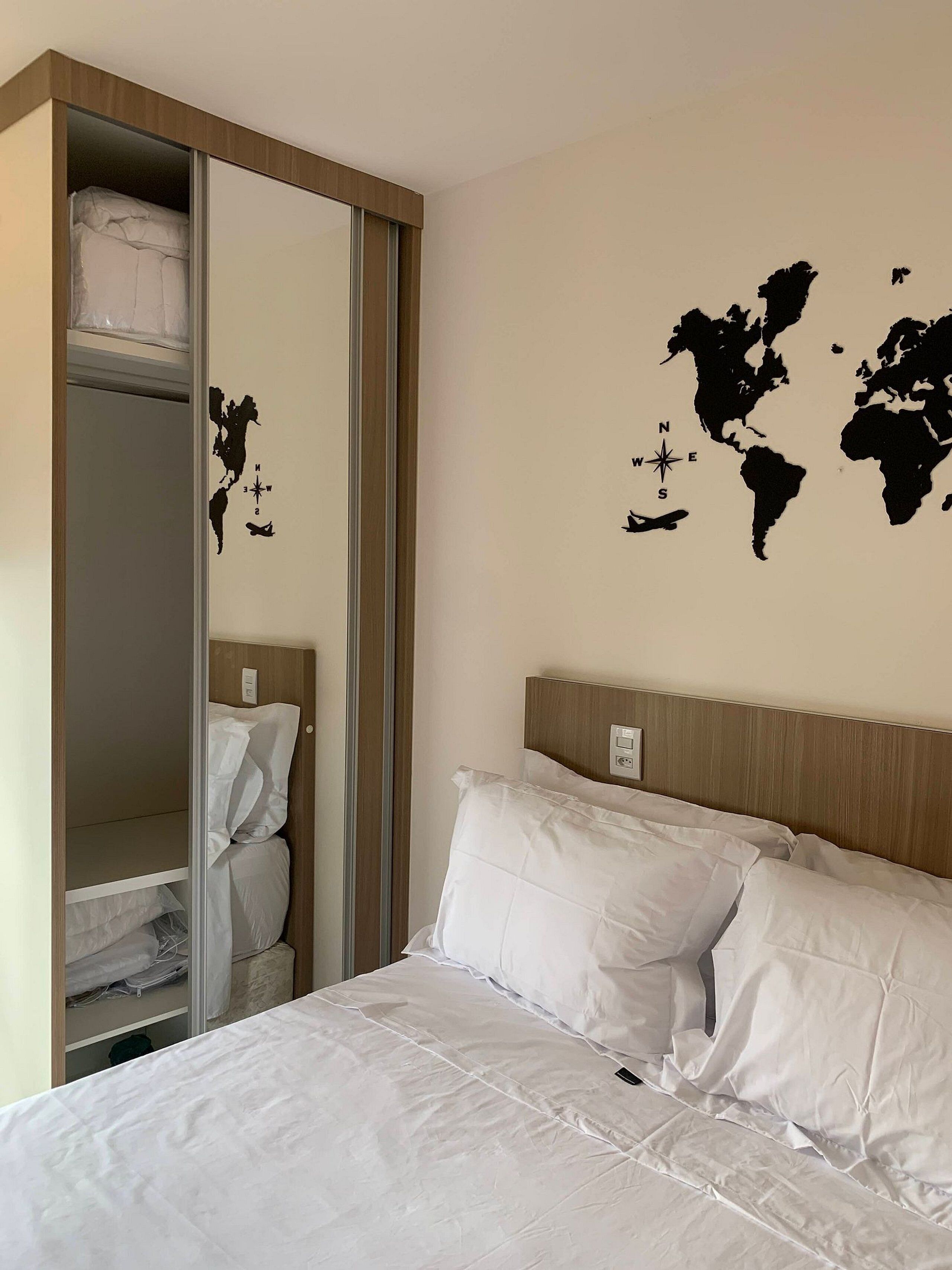 Una habitació d'hotel amb un llit, un armari i un mapa del món a la paret.