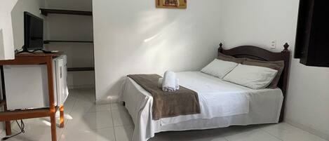 A bedroom with a bed, a desk, and a ceiling light.