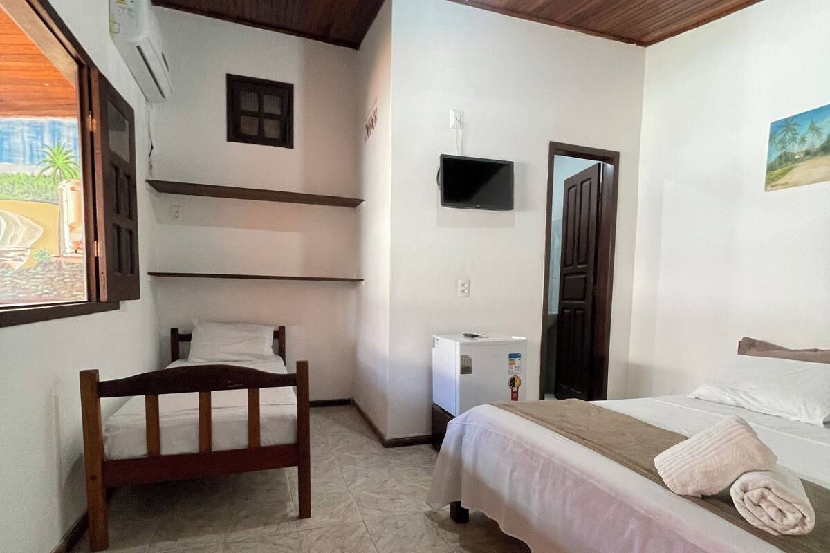 A bedroom with a bed, a chair, a TV, and a door.