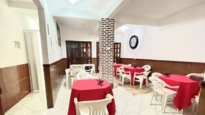 A dining area with multiple tables and chairs, a brick pillar, and a clock on the wall. - Pousada Vila Nova (Cairu)