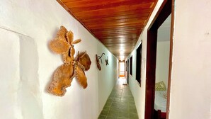 A hallway with a wooden ceiling, a butterfly sculpture on the wall, and a red mat at the end. - Pousada Vila Nova (Cairu)