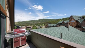 Ein Balkon mit Grill und Blick auf eine Stadt und Berge.