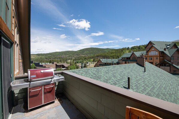 A balcony with a grill and a view of a town and mountains. - Select Unit 1710 - 2br - Zephyr Mountain Lodge 2 Bedroom Condo (Winter Park)