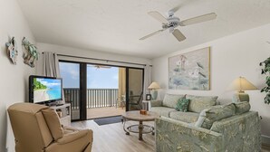 Una sala de estar con sofá, sillón reclinable, televisor y ventilador de techo.