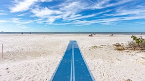 A beach with a blue running track leading to the water, a few people in the distance, and a clear sky. - Beach Villas # 306 by RedAwning - 15% off through September 2024 (Fort Myers Beach)