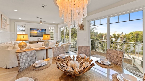 Un salon spacieux avec une grande table à manger, des sièges confortables, un téléviseur et un balcon offrant une vue sur le paysage environnant.