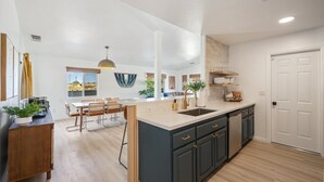 Une cuisine spacieuse dotée d’un îlot central, de meubles de rangement aux couleurs sombres et donnant sur l’espace de vie.