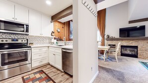 A modern kitchen with stainless steel appliances, white cabinetry, and a patterned backsplash.