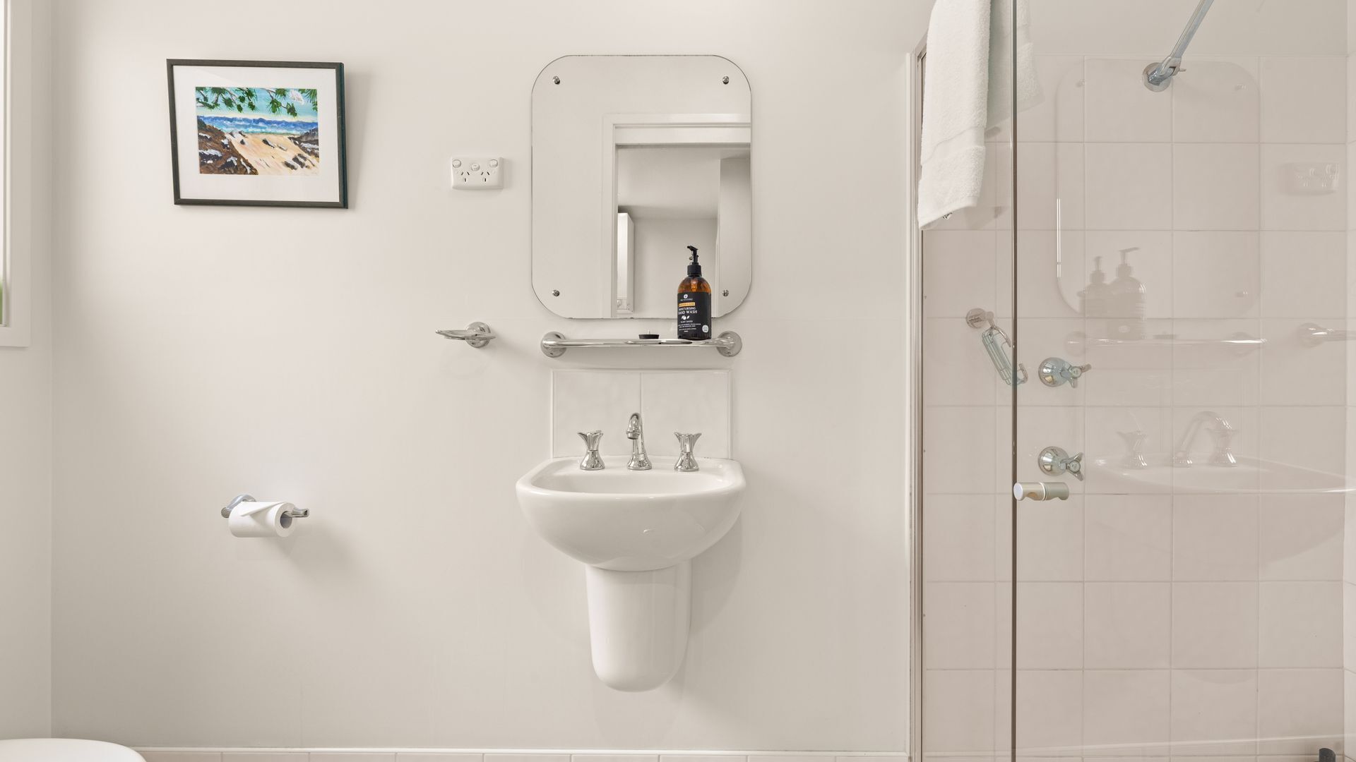 Une salle de bain avec un lavabo, un miroir et une douche.
