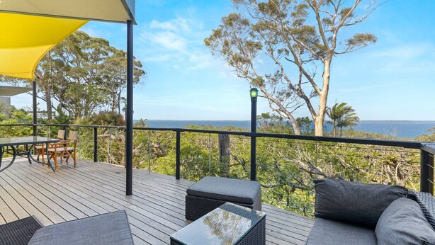 An outdoor deck with wooden flooring, a yellow canopy, and outdoor furniture. - Blue Point House by Experience Jervis Bay (Vincentia)