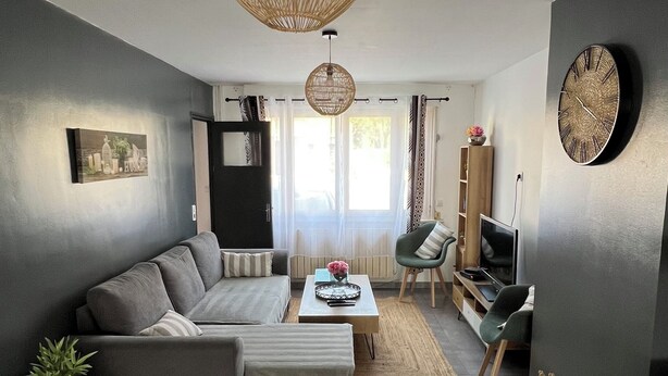 A modern living room with a grey sofa, a coffee table, and a large woven pendant light. - Maison de Ville (Cambrai)