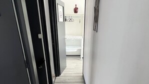 A hallway with a wooden floor, white walls, and a door leading to a bathroom. - Maison de Ville (Cambrai)