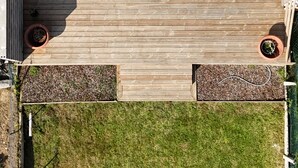A top-down view of a deck with a wooden floor, surrounded by a metal railing, and furnished with a table and chairs. - Maison de Ville (Cambrai)