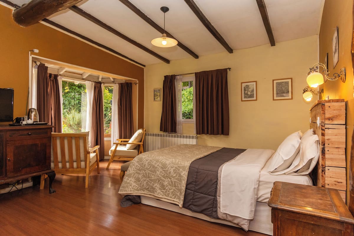 A bedroom with a bed, wooden furniture, a chair, a dresser, and a window with curtains.