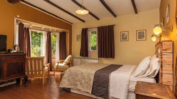 Un dormitorio con cama, muebles de madera, una silla, cómoda y ventana con cortinas.