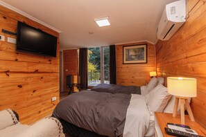 Et hotelværelse med en seng, et fjernsyn hængt på væggen, et klimaanlæg, et maleri og en lampe på et natbord.