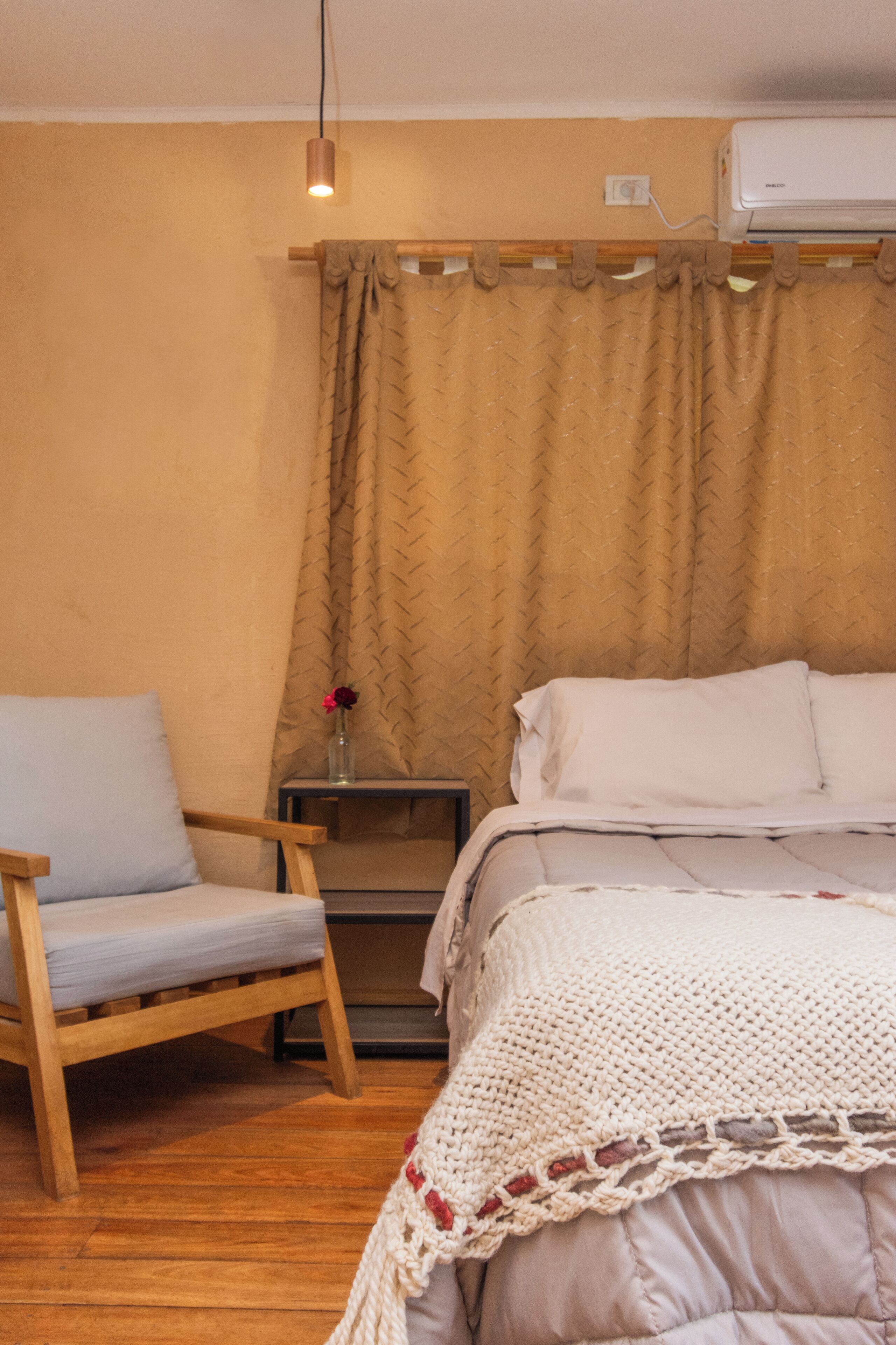 Ein Schlafzimmer mit Bett, Sessel, Nachttisch und Klimaanlage.