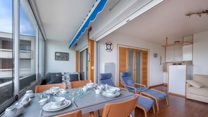 A modern dining area with a table set for four, surrounded by orange chairs. There is a view of the city through large windows. - 500m from the beach, flat for 2 (La Baule-Escoublac)