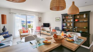 A modern living room with a dining area, large windows, and a bookshelf. - 25m from the beach, seaview, flat for 4 (Erquy)