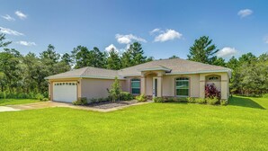 A two-story house with a garage, a front yard with a lawn, and trees in the background. - 5 Mi to Weeki Wachee Springs! Poolside Retreat (Brooksville)