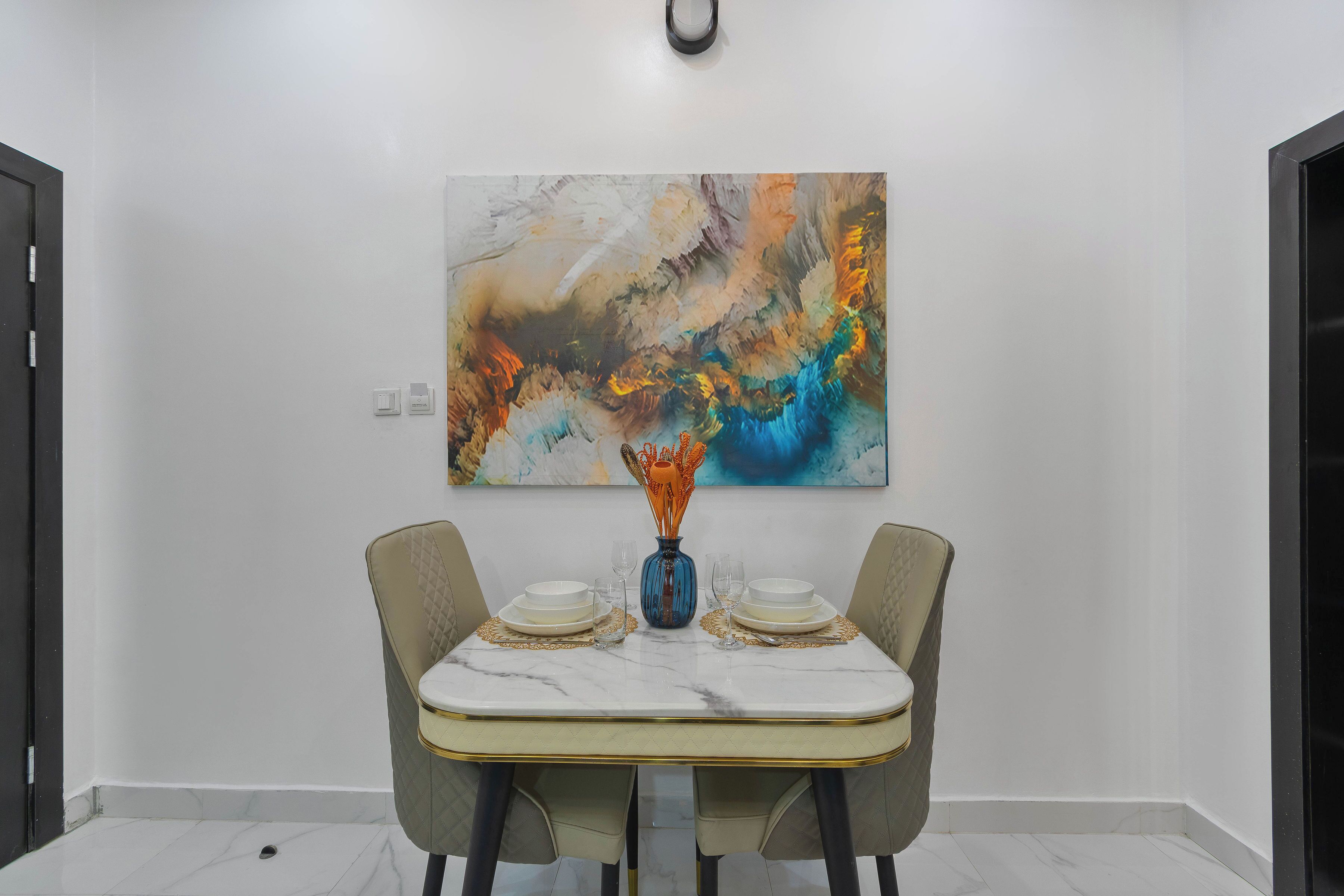 A dining area with a marble table, two chairs, and a centerpiece.