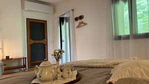 Ein Schlafzimmer mit einem Bett, einem Nachttisch, einem Fenster mit Vorhängen und einer Tür.