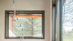 A room with two large windows, a wooden ceiling beam, and a hanging light fixture.