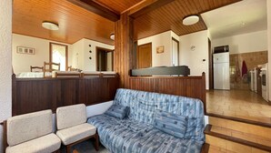Un salon chaleureux avec un canapé, deux fauteuils et un plafond en bois.