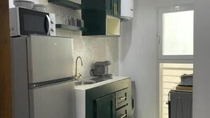 A compact kitchen with a refrigerator, microwave, and a green cabinet with drawers. - Appartement Haut Standing à Dakar-résidence Mixta (Dakar)