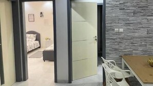A modern room with a bed, a desk, and a chair. There is a door leading to another room. - Appartement Haut Standing à Dakar-résidence Mixta (Dakar)