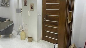 A modern interior with a wooden door, a gray sofa, and a small decorative plant. - Appartement Haut Standing à Dakar-résidence Mixta (Dakar)
