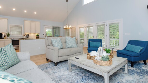 A spacious living area with a sofa, chairs, a coffee table, and a kitchen in the background.