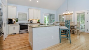 A spacious kitchen with white cabinets, a granite countertop, and a central island.