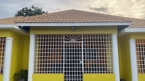 A yellow building with a tiled roof, white columns, and a metal gate. - Cool Breeze at Secret Hideaway
Ocho Rios (Ocho Rios)
