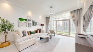 Een moderne woonkamer met een bank, salontafel en een groot raam met gordijnen.