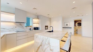 Een moderne keuken met een marmeren kookeiland, ingebouwde apparatuur en een strak design.