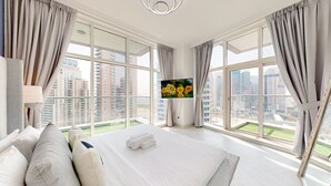 Een hotelkamer met een groot bed, een televisie en een balkon met uitzicht over de stad.