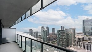 A balcony with a city view, featuring high-rise buildings and a clear sky.