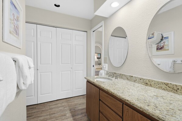 A bathroom with a sink, two mirrors, a white door, and a towel rack.