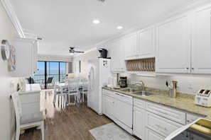 A modern kitchen with white cabinets, a granite countertop, a coffee maker, and a toaster. - Beachfront paradise with direct beach access! (Bradenton Beach)