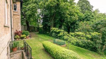 Relax in a serene garden with well-maintained hedges and potted plants, featuring a comfortable bench.