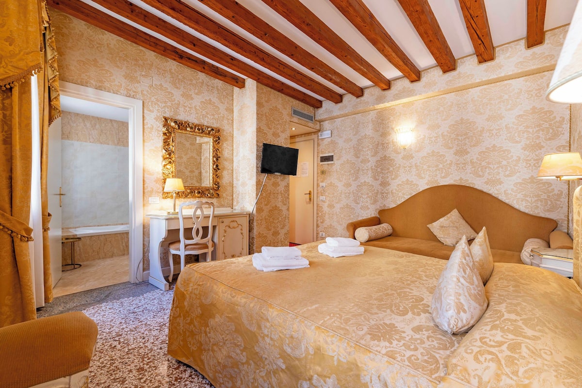 A hotel room with a bed, a desk, a chair, and a television.
